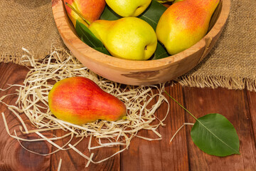 Red and yellow pears with leaves on the rustic table
