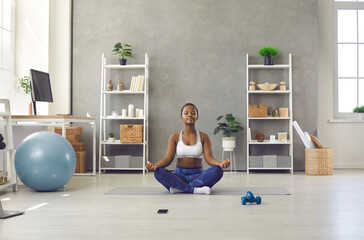 Calm millennial African American girl meditate practice yoga at home on lockdown. Relaxed young black woman have meditation session online, relieve negative emotion breathe fresh air.