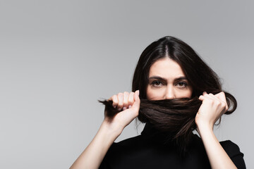 Obraz premium young woman covering mouth with brown hair isolated on grey