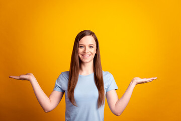 Photo of young cheerful girl hold hands solution promotion advertise isolated over yellow color background