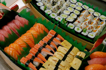 multi selection of japanese food sushi rolls in a boat, includes salmon, tuna, crab, shrimps etc.