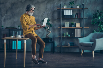 Photo of busy mature guy dressed yellow shirt spectacles chatting modern gadget indoors workplace...