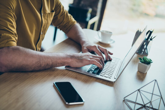 Photo of mature guy arms hands dressed yellow shirt communicating modern gadget indoors workplace workstation