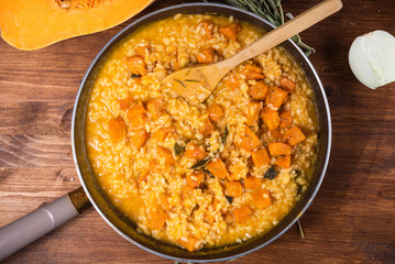 Cooking risotto with pumpkin - risotto in a pan with chunks of baked pumpkin, top view, close-up