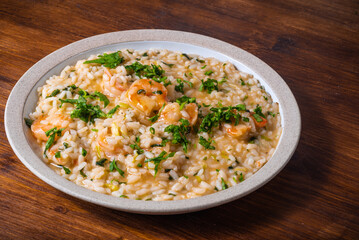 Fototapeta na wymiar Portion of shrimp risotto sprinkled with chopped parsley on a plate, close-up