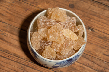 The rock sugar in the container is on the wood grain table