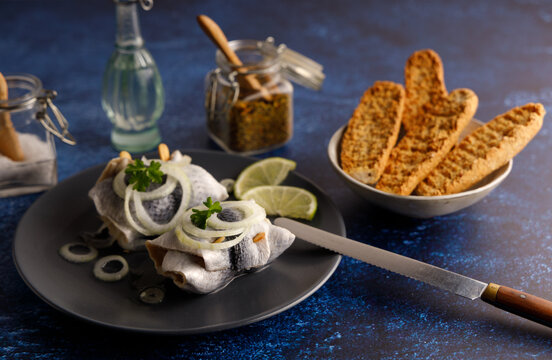 pickled herring on a plate. Seafood, pickled herring marinated in vinegar and onions on a plate. Served on a dark table top.