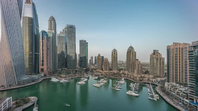 Dubai marina tallest skyscrapers and yachts in harbor aerial day to night timelapse.
