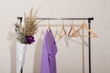 One sweater in purple lavender very peri colors, eco reusable bag and empty hangers on a rail. Sustainable fashion.