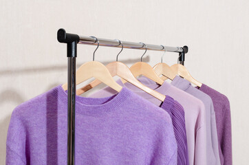 Fashionable tops in trendy purple, very peri, lavender colors hanging on a shopping rail. 