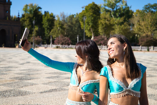 Two belly dancers are taking a photo with their mobile phones. They are dressed in light blue and are having fun. Concept of friendship and happiness