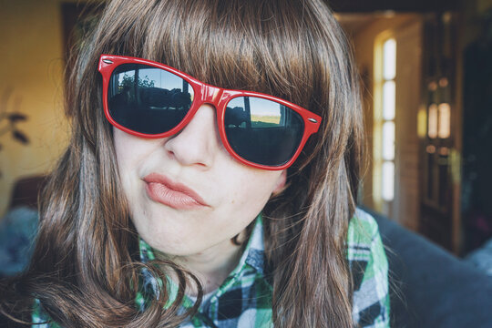 Funny portrait of a young woman wearing red sunglasses