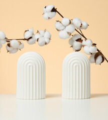 podium with white flower cotton and arches to showcase cosmetics, products and other goods, beige background