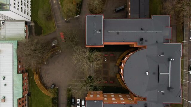 City apartment building rooftops and yards with vehicles parked, aerial top down view
