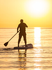 A man sailing on a SUP board on the sea. Stand up paddleboarding.