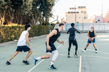 Fototapeta premium Four multicultural friends playing basketball outdoors