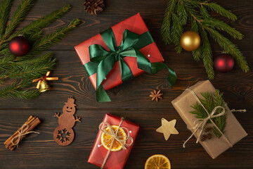 Fototapeta na wymiar Christmas gifts and branches of Christmas tree on dark wooden background.