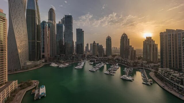 Sunrise over Dubai marina tallest skyscrapers and yachts in harbor aerial morning timelapse.