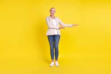 Full length photo of mature lady demonstrate promotion offer advertise isolated over yellow color background