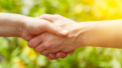 Hände geben Handschlag vor grüner Natur als Deal Konzept