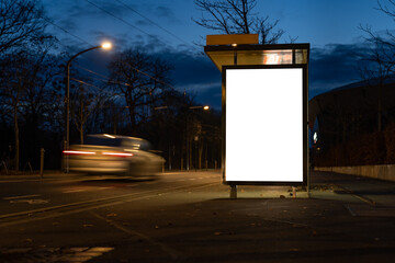 Blank advertisement board as a mock-up template in the city. Empty screen at a bus stop during the night. A car driver is passing by very fast.