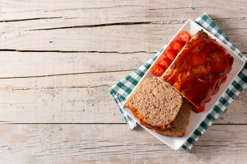 Traditional American meatloaf with ketchup on rustic wooden table. Copy space