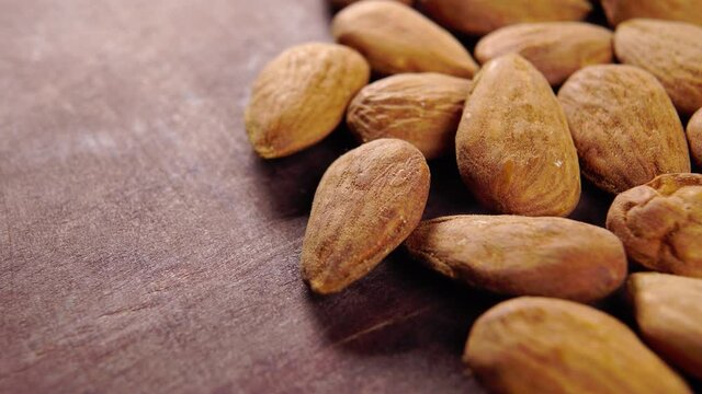 Almond kernels on a rustic wooden surface. Dry nuts close up. Macro. Rotation