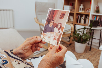 Portrait of elderly woman hands looking at old picture of her dead husband made many years ago....