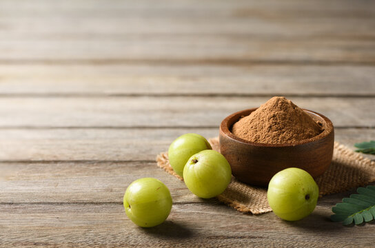 Close-up of Fresh Amla (Indian gooseberry) fruits powder in wooden bowl.