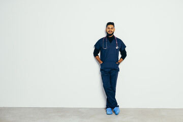 Young handsome Indian man doctor against gray background