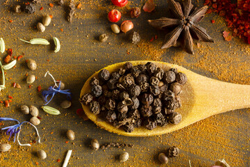 Black peppercorns on wooden spoon