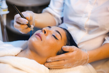 Beautician hands making mesotherapy injection with dermapen on client's face in spa salon....