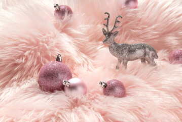 Creative layout with silver glitter reindeer decoration and pink baubles on pastel pink faux fur...