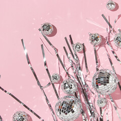 Christmas party creative layout with disco balls decoration and silver foil fringe curtain on pastel pink background. 80s or 90s retro fashion aesthetic party concept. New Year celebration idea.