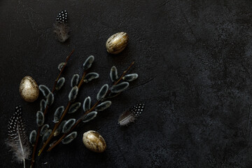 Happy Easter concept. Preparation for holiday. Golden decorated easter eggs willow feather on trendy grunge scratched dark black shale background. Simple minimalism flat lay top view copy space