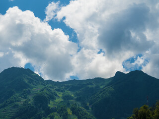 A beautiful view of the mountains with clouds and paragliders fly in the distance. Rosa Khutor