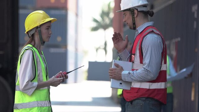 Engineer shaking hands with foreman team in hardhat and safety vest control loading containers box from cargo, Dock worker team in a shipyard, Logistic concepts.