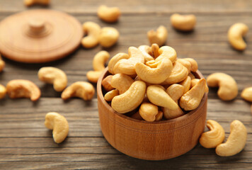 Cashew nuts on wooden bowl on brown background. Top view.