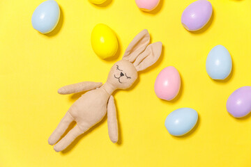 Happy Easter concept. Preparation for holiday. Colorful decorated easter eggs and bunny toy isolated on trendy yellow background. Simple minimalism flat lay top view copy space