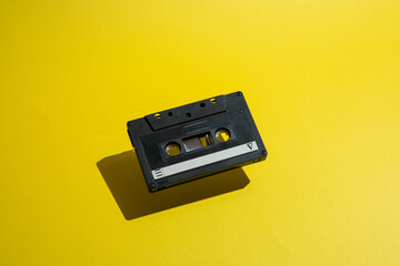 Black audio cassette, tape on a yellow background. Cool musical and retro idea
