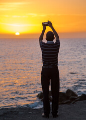 A man with a camera takes pictures of the sunset