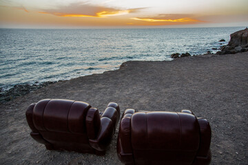 Two leather chairs on the beach and sunset