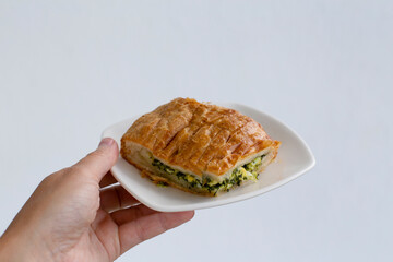 A small slice of spinach . Healthy breakfast. Hand holding a plate of pie