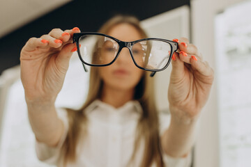 Woman choosing spectacles at optic lab