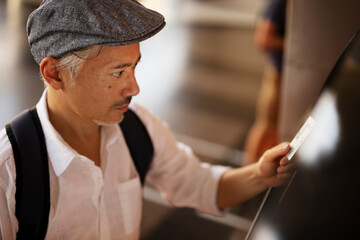 Naklejka na ściany i meble Senior man withdrawing money from credit card. Man typing pin code on keypad of ATM mashine...