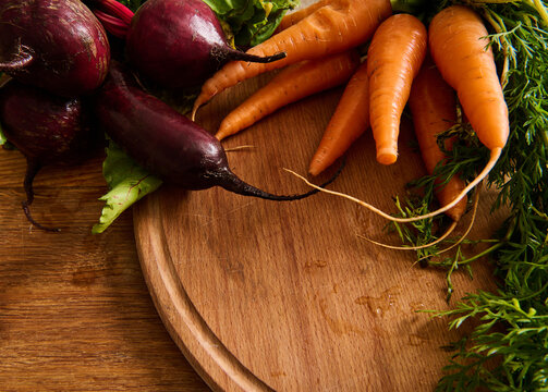 Bunches Of Fresh Organic Beets And Baby Carrots With Tops On A Wooden Cutting Board. Vegan Food Background.