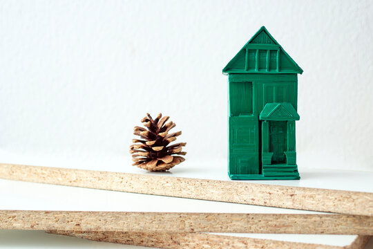 white chipboards edges and a green miniature house, and a pine cone