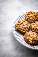 galletas de avena en un plato blanco sobre un fondo gris claro con espacio en blanco