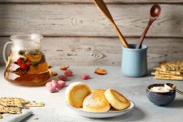 Appetizing syrniki (curd pancakes), with powdered sugar and tender yogurt. Delicious and hearty breakfast with natural, fruit and berry tea.