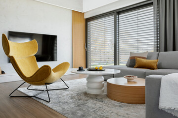 Modern living room interior design with corner beige sofa, creative rounded coffee tables, mustard...